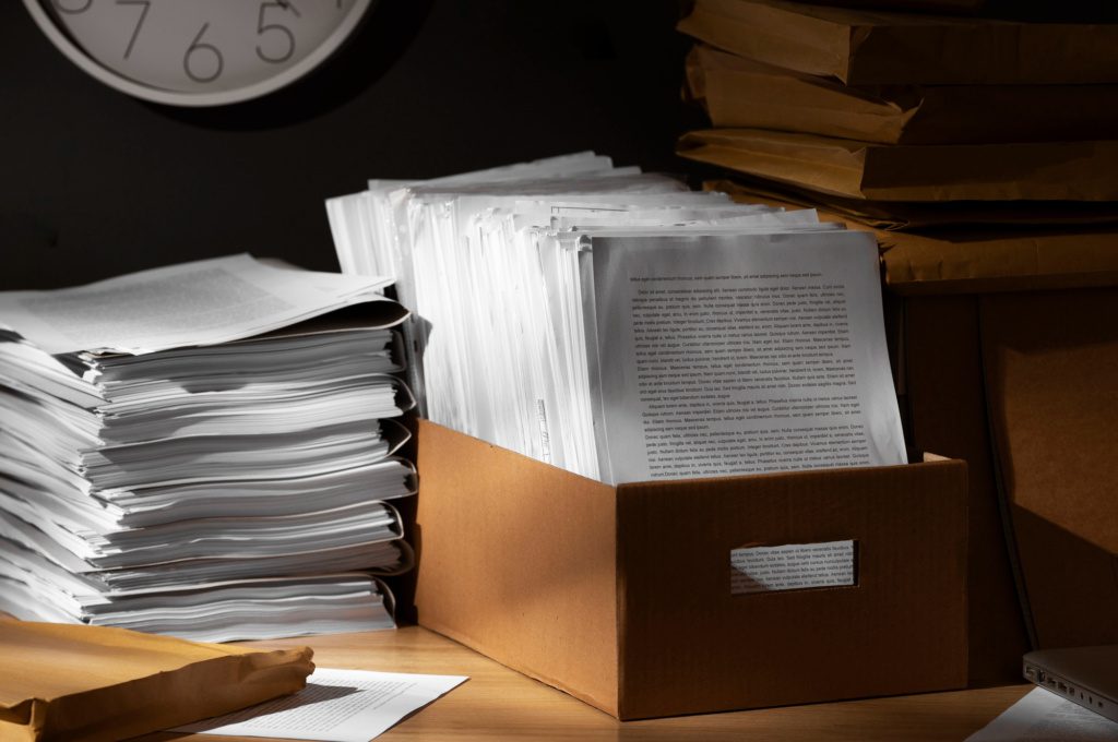 Photograph of docs in boxes on a table in the corner of an office.