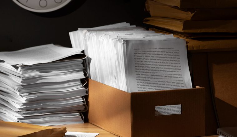 Stacks of important paper records and documents stored in a box and envelopes, illustrating the need to protect important records from natural disaster.