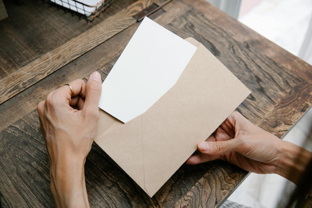 Featured image for IRS mailing address change: hands placing a document into a kraft envelope on a wooden desk.
