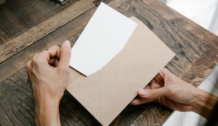 Featured image for IRS mailing address change: hands placing a document into a kraft envelope on a wooden desk.