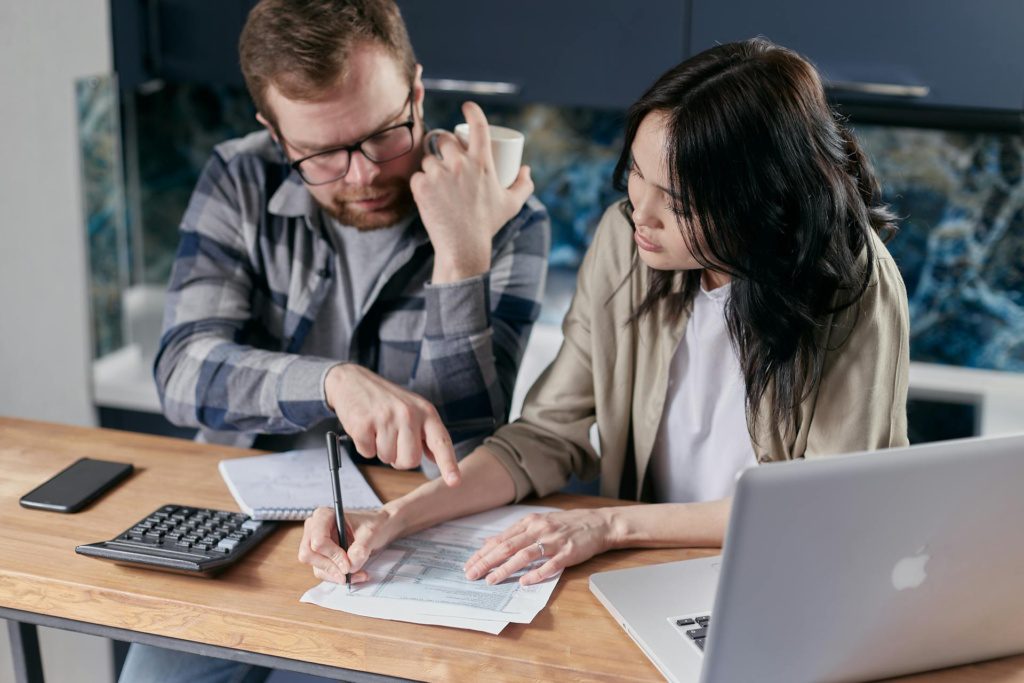 Featured image for One Big Beautiful Bill Act deductions: two people reviewing a pay stub with a calculator at a kitchen table.
