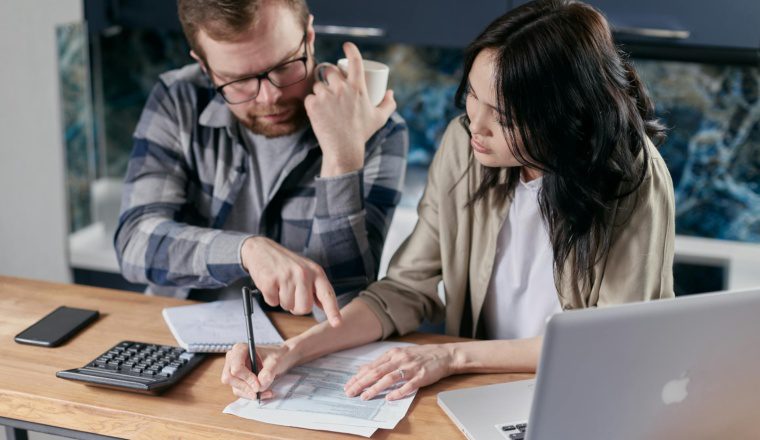Featured image for One Big Beautiful Bill Act deductions: two people reviewing a pay stub with a calculator at a kitchen table.