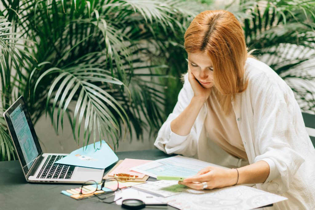 Woman reviewing tax forms and payroll information on a laptop, representing IRS penalty relief for tip and overtime reporting in 2025.