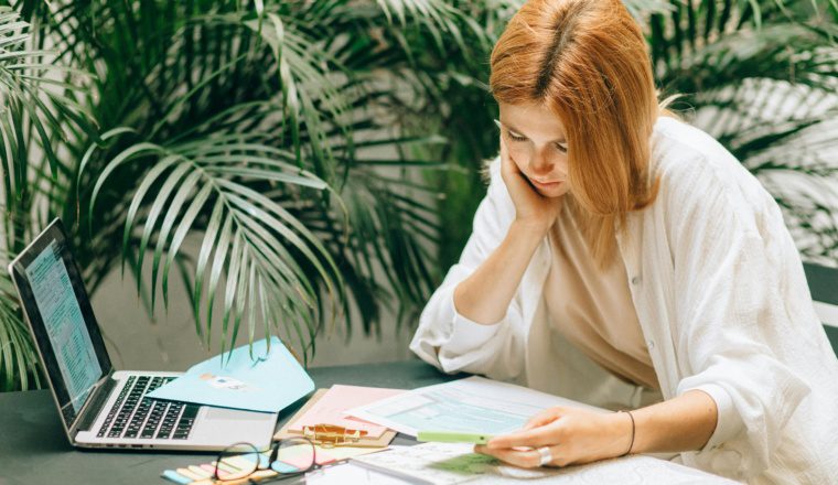 Woman reviewing tax forms and payroll information on a laptop, representing IRS penalty relief for tip and overtime reporting in 2025.