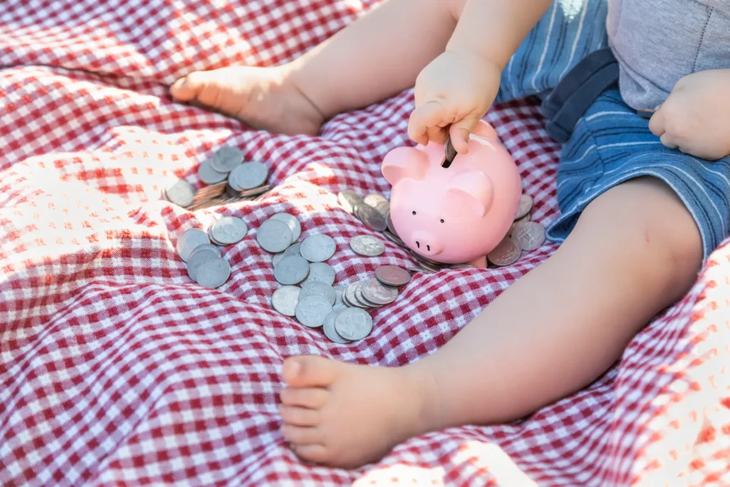 A baby saving money in a piggy bank, representing the $1,000 contribution from the Trump Accounts pilot program for eligible children.